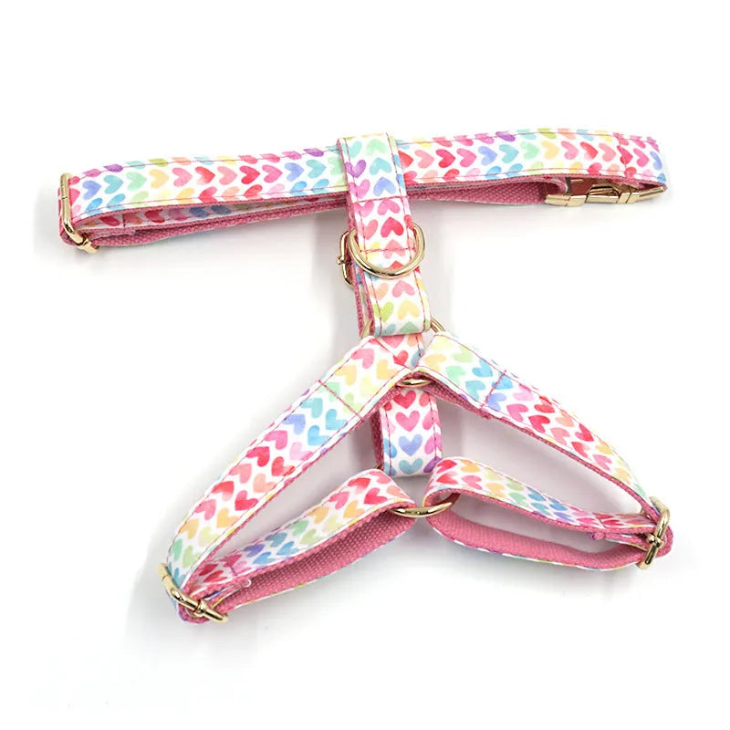 Pink colourful dog harness with gold buckle and heart-shaped stones on chest and back strap.