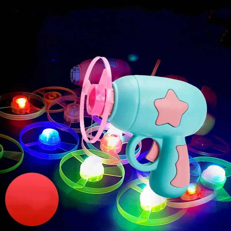 Plastic flying saucer launcher toy set with LED lights and coloured discs on outdoor grass.
