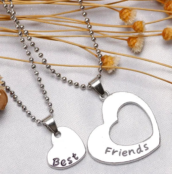 Two matching silver heart-shaped cross chain necklaces on a surface, alloy construction