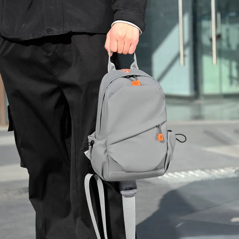 Men's black polyester crossbody bag with a single shoulder strap, shown in a casual setting.