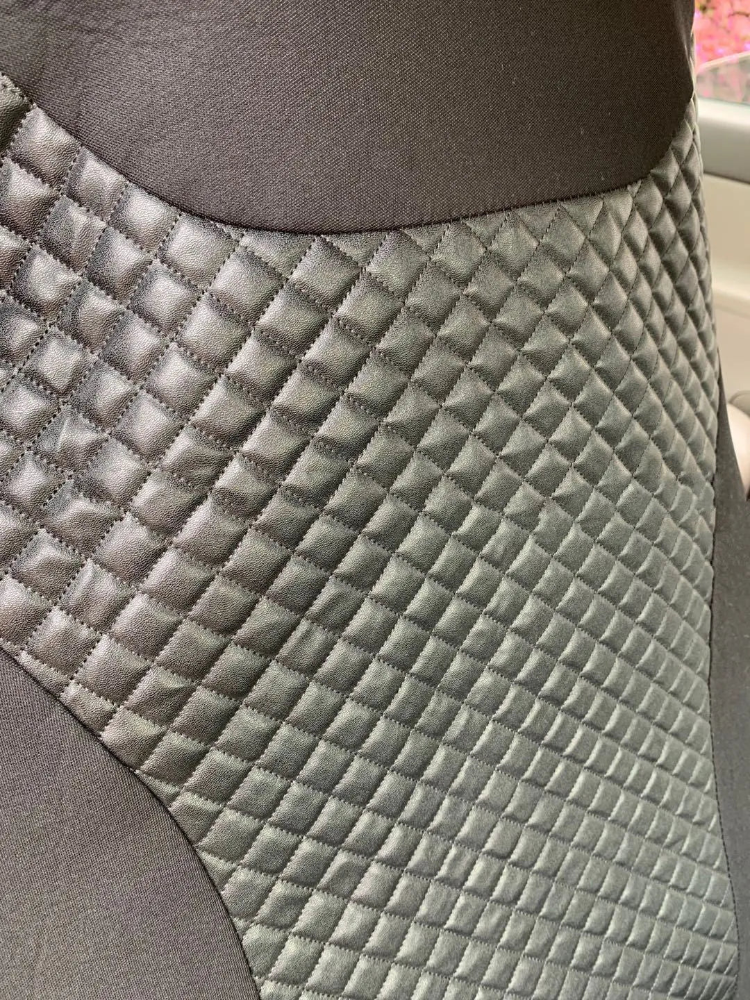 Black quilted car seat cover made of PU and polyester fabric with sponge padding.