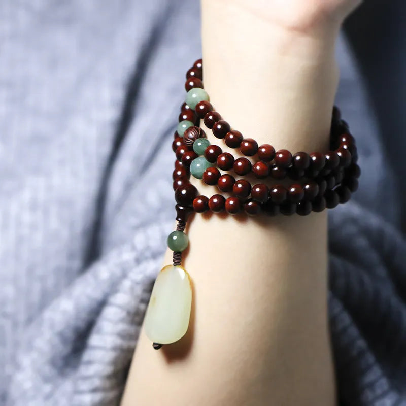 Close-up of a rosewood bead bracelet with 108 beads and a carved Hotian jade pendant.
