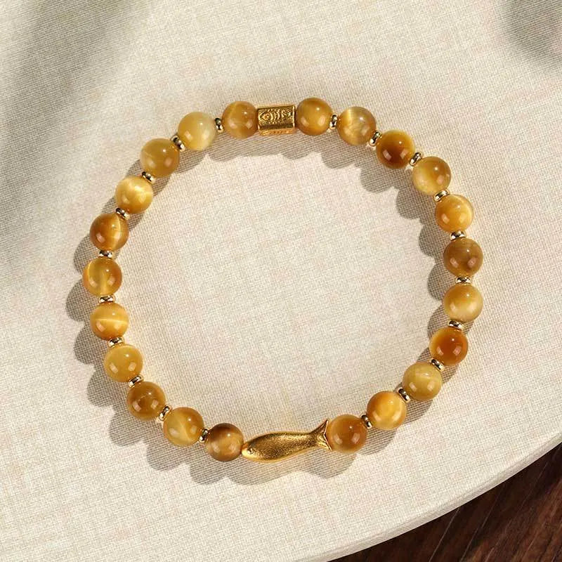 Women's tiger eye bracelet with small gold fish charm on adjustable band