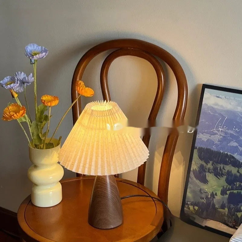 Tapered floral ceramic table lamp with remote control on a wooden surface.