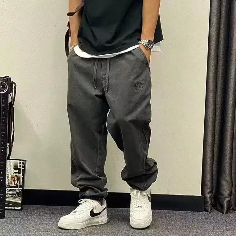 Men's black cotton harem pants with elastic waist and drawstring, cropped ankle bandage leg, side view