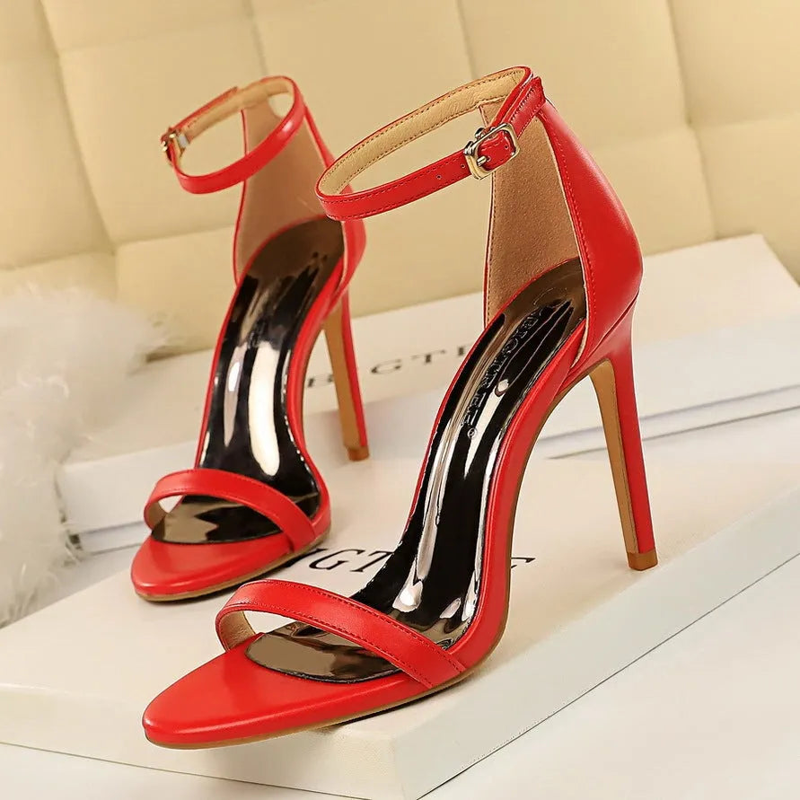 Open-toe high heels with ankle strap and buckle closure in solid colours on white background