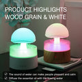 White rain cloud shaped ultrasonic humidifier and aromatherapy diffuser with coloured lights on a wooden table.