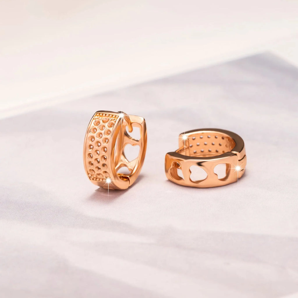 Rose gold women's earrings with a hollowed out heart shape and circular frame.