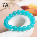 Natural blue-green Amazonite scattered loose beads in various sizes next to a finished crystal bracelet.