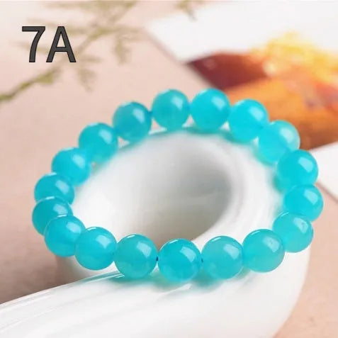 Natural blue-green Amazonite scattered loose beads in various sizes next to a finished crystal bracelet.