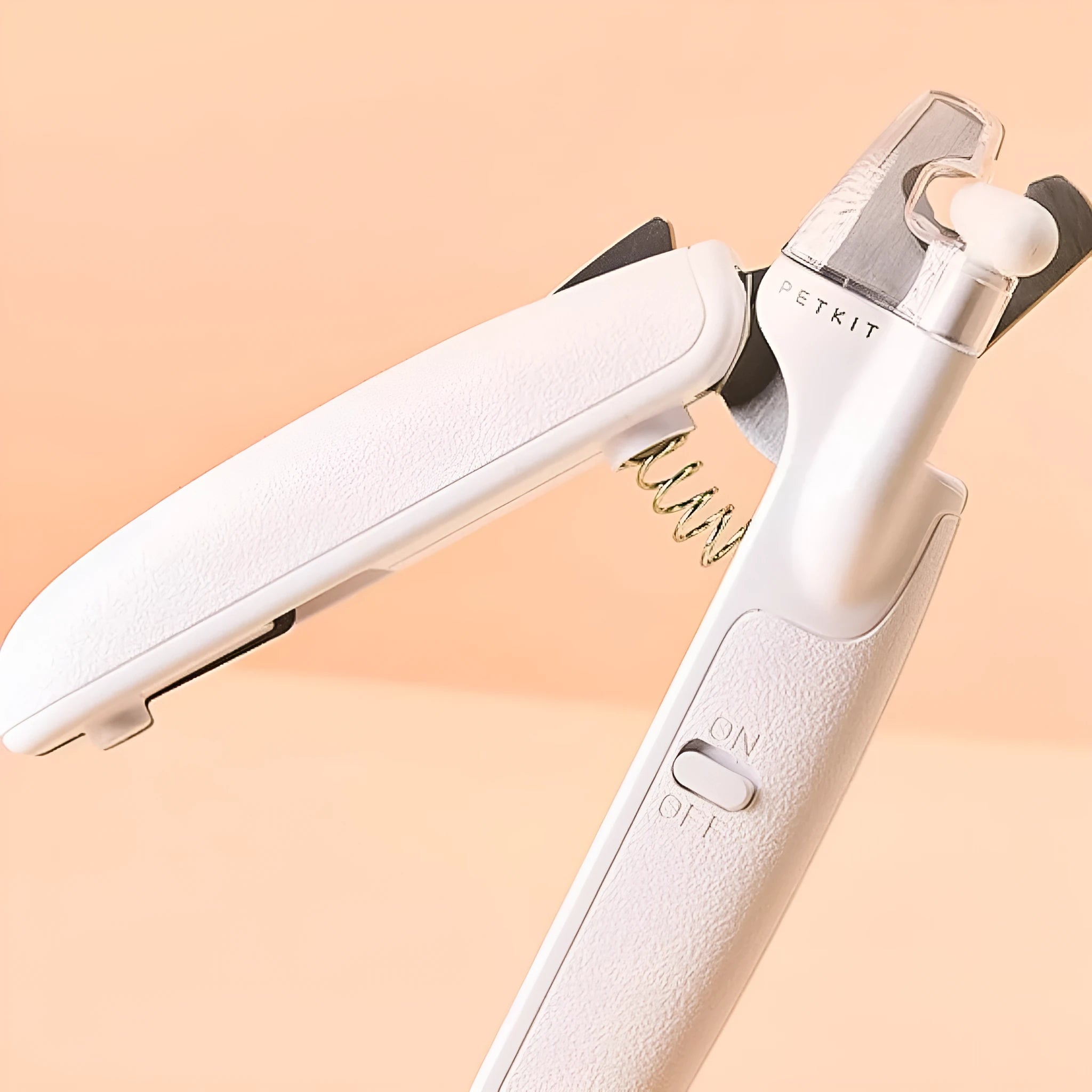 White pet nail clippers with LED light, transparent guard, and nail file on a grey background.