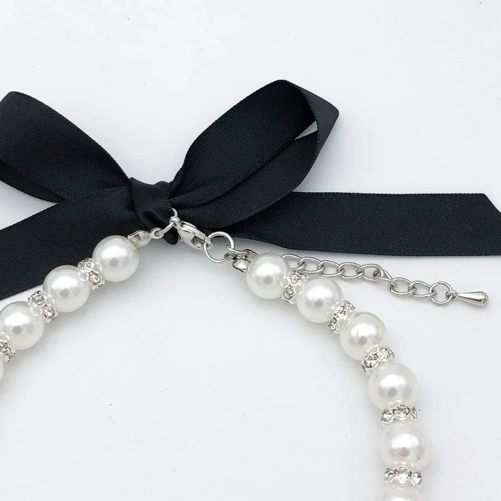 Adjustable blue pearl and rhinestone dog necklace with ribbon bow on a small dog.
