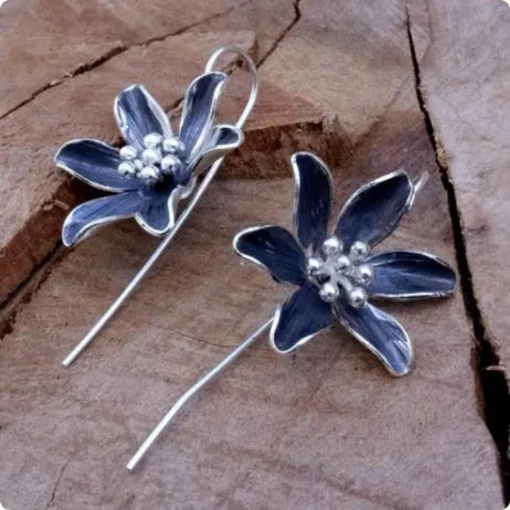 A pair of retro-style purple flower-shaped alloy earrings for women on a plain background.