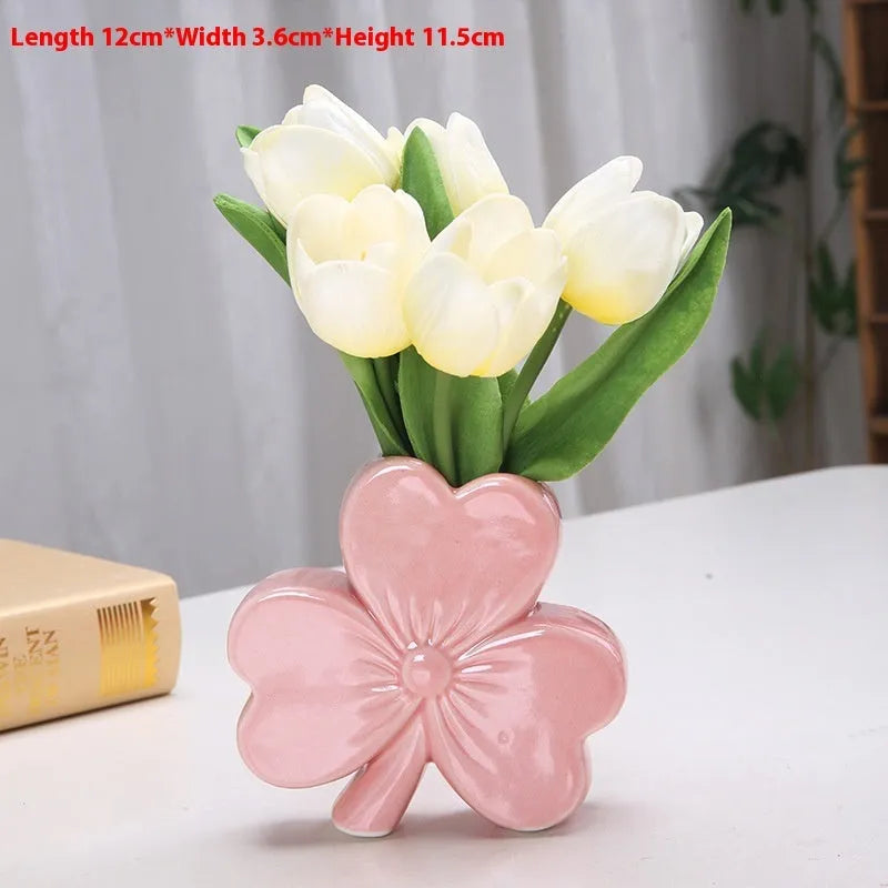 Small clover-design ceramic vase in pink, red, light green, or white on a desktop.