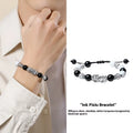 Sterling silver blessing card attached to a hand-woven black and white couple bracelet set with tassel details.