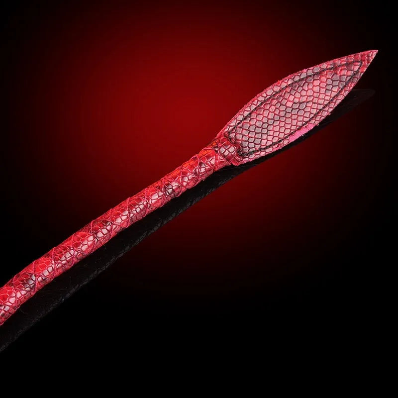 Red PU willow leaf whip for BDSM training and role play, lying on a surface.