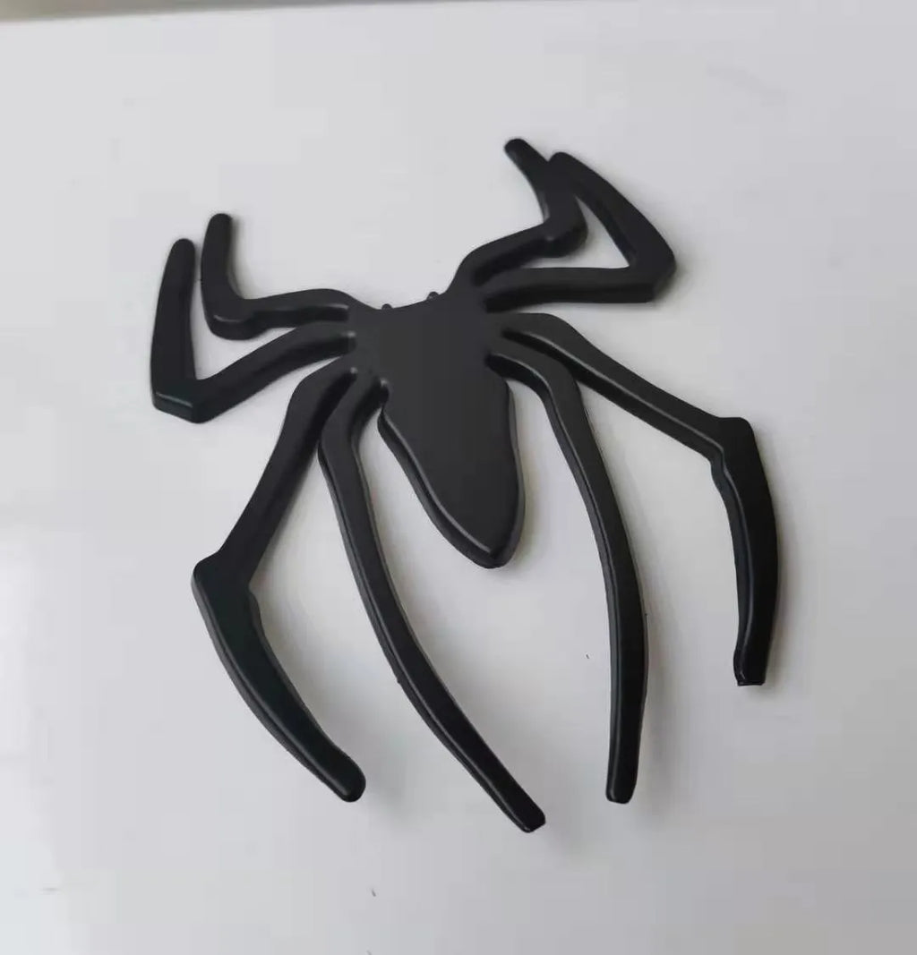 Three-dimensional metal spider bumper sticker in metallic finish.