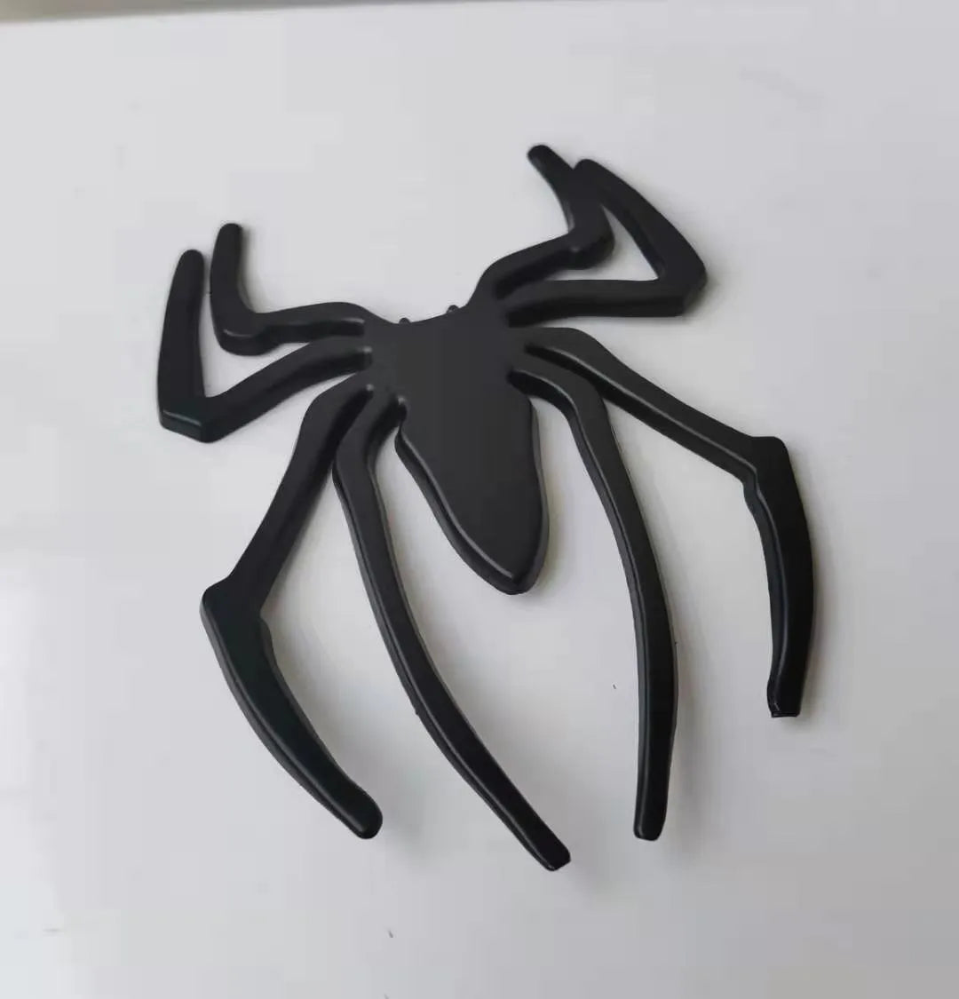 Three-dimensional metal spider bumper sticker in metallic finish.