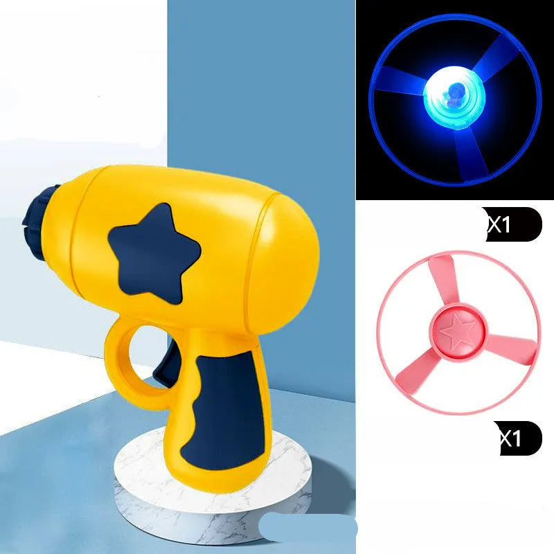 Plastic flying saucer launcher toy set with LED lights and coloured discs on outdoor grass.