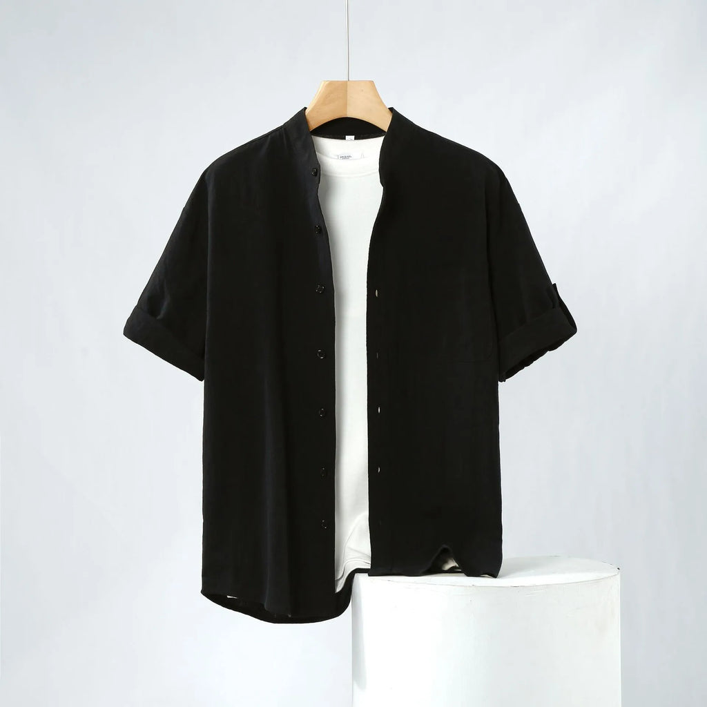 A man's loose-fitting, short-sleeved linen shirt in a solid colour with a stand collar.
