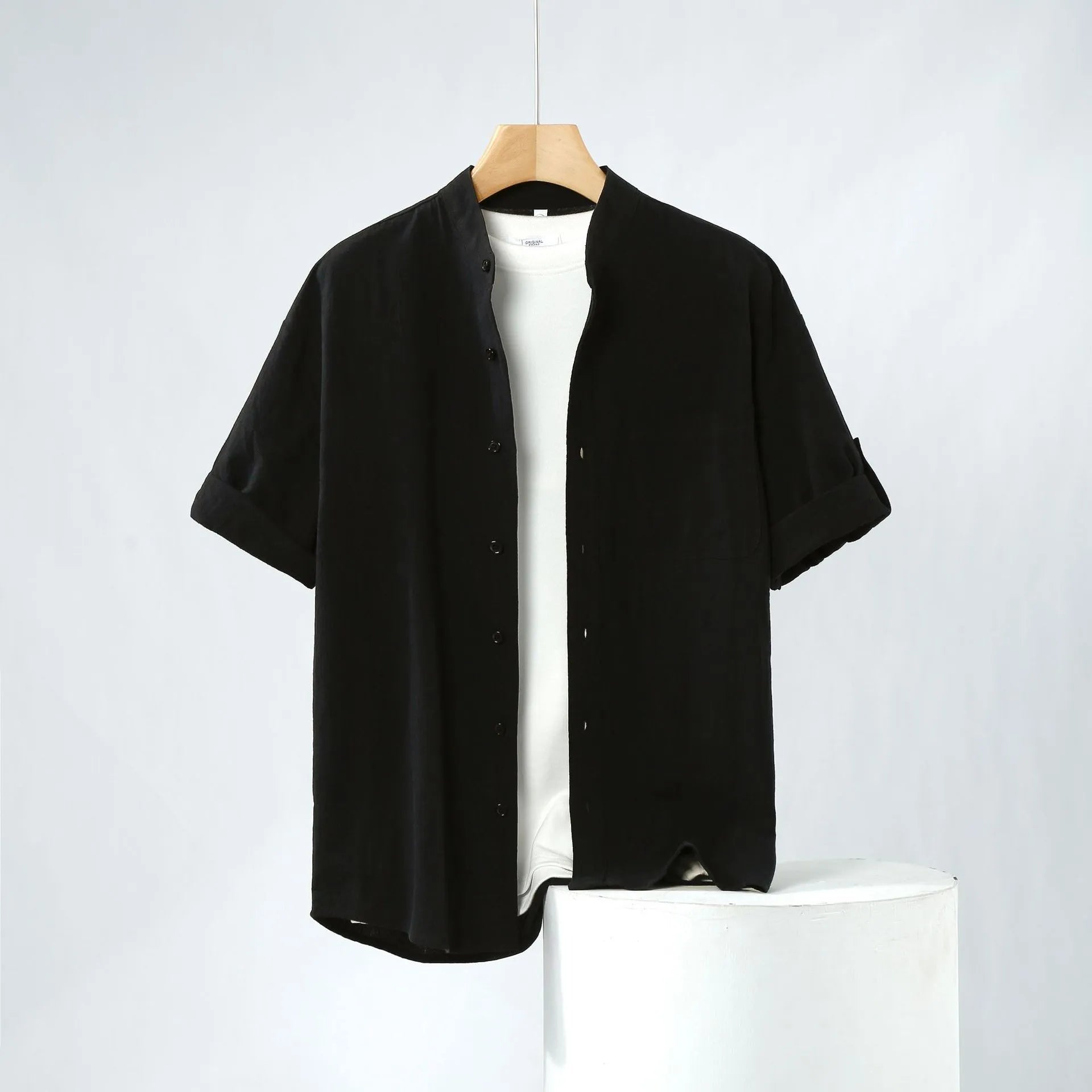 A man's loose-fitting, short-sleeved linen shirt in a solid colour with a stand collar.