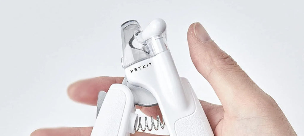 White pet nail clippers with LED light, transparent guard, and nail file on a grey background.