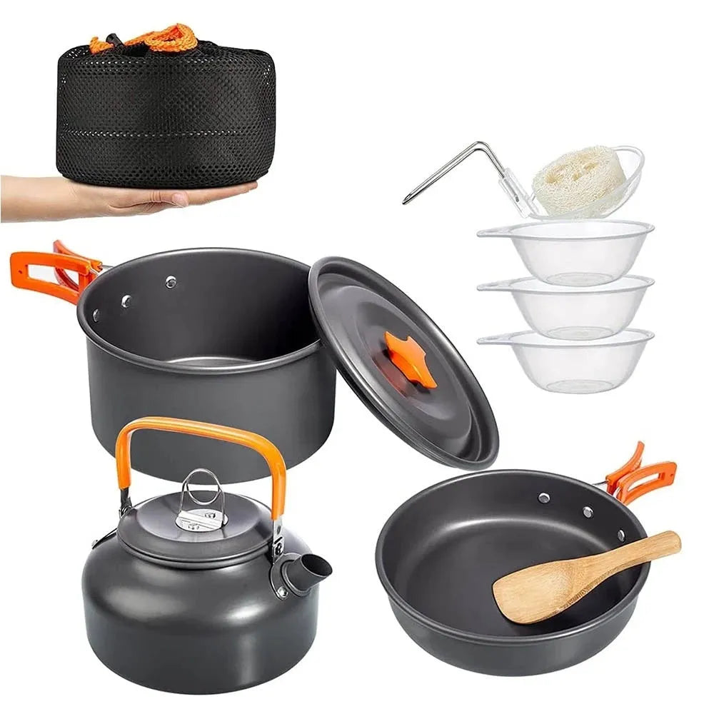 Orange folding camping cookware set with pots, pan, spoons, bowls in mesh bag on outdoor table