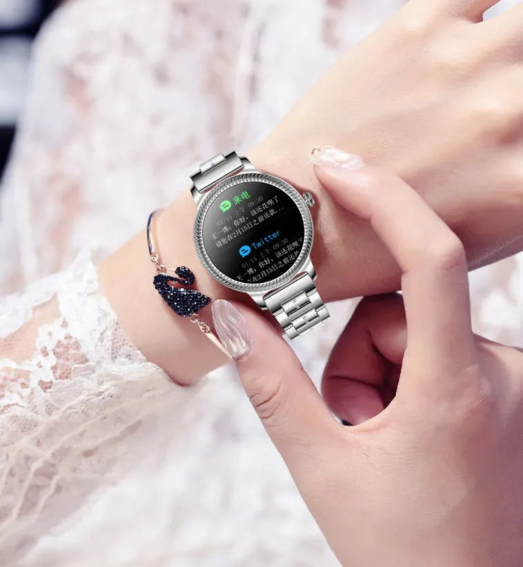 AK38 ladies smart watch with stainless steel band on wrist, showing colour screen.