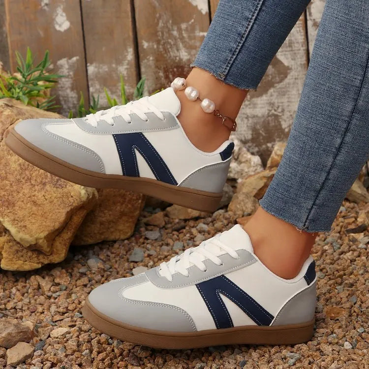 Blue women's low-top hiking shoes with rubber sole and lace-up design on an outdoor background.