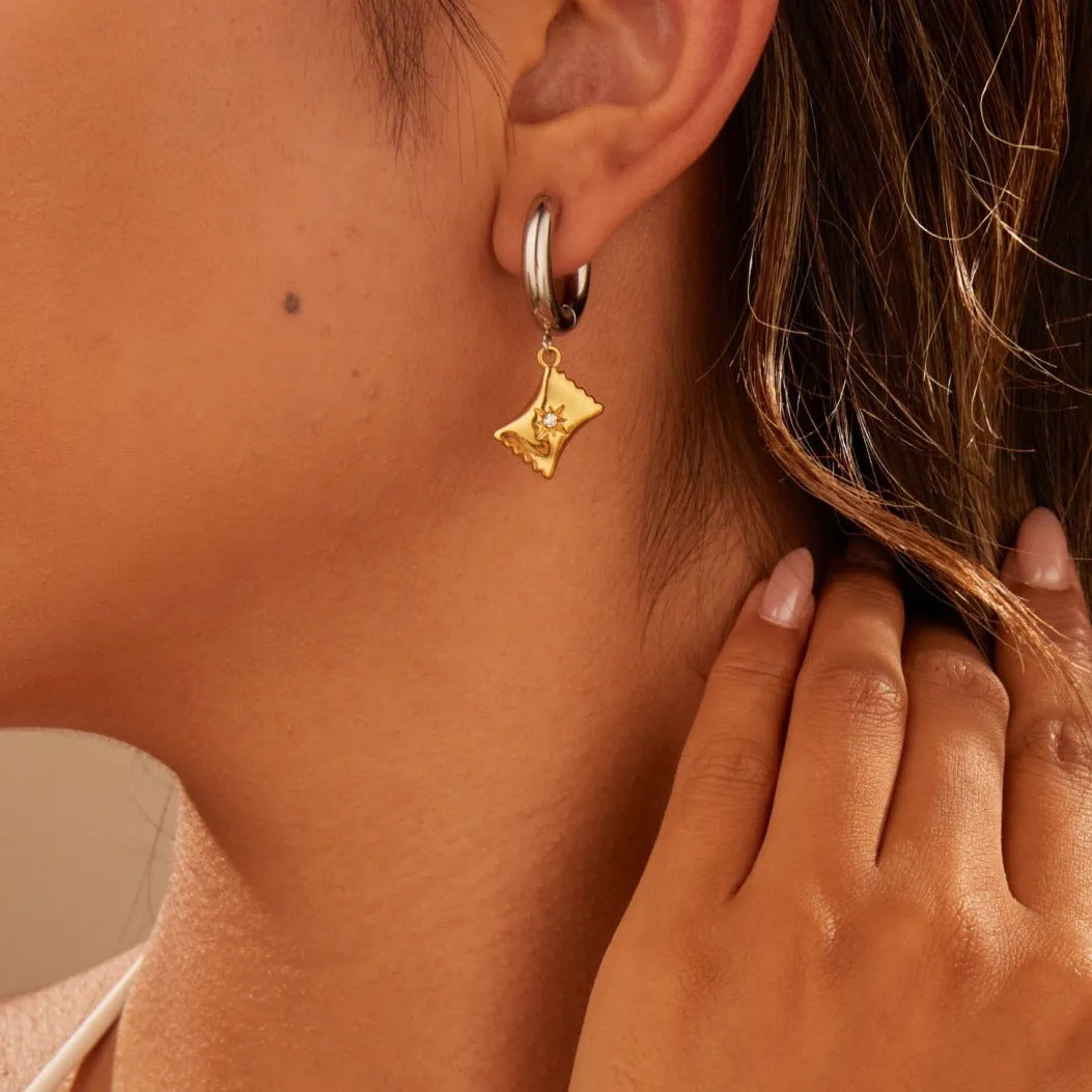 A pair of stainless steel earrings with 18K gold plating in a Christmas tree and heart shape design.