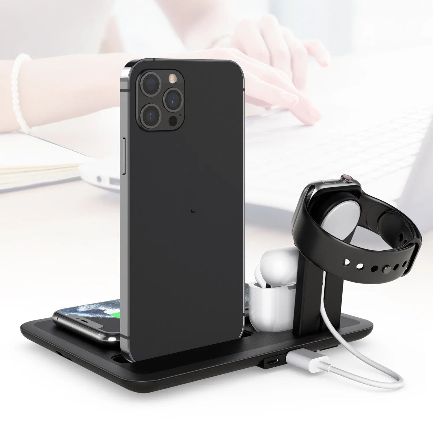 Black wireless charging bracket holding an iPhone vertically, with AirPods and an Apple Watch on its base.