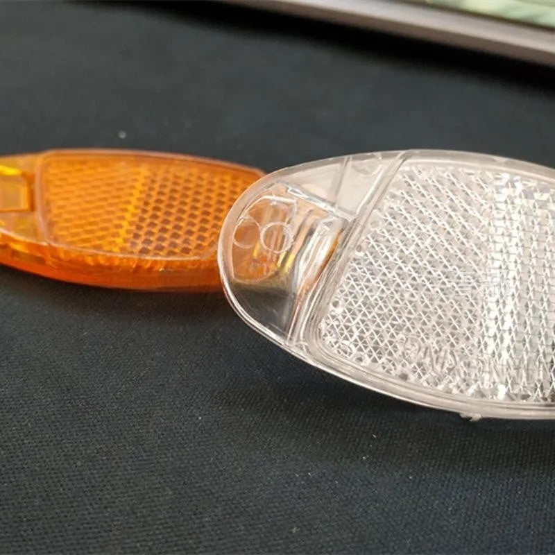 White and yellow plastic bicycle spoke reflector for wheel safety, dimensions 7.2cm long by 3.5cm wide.