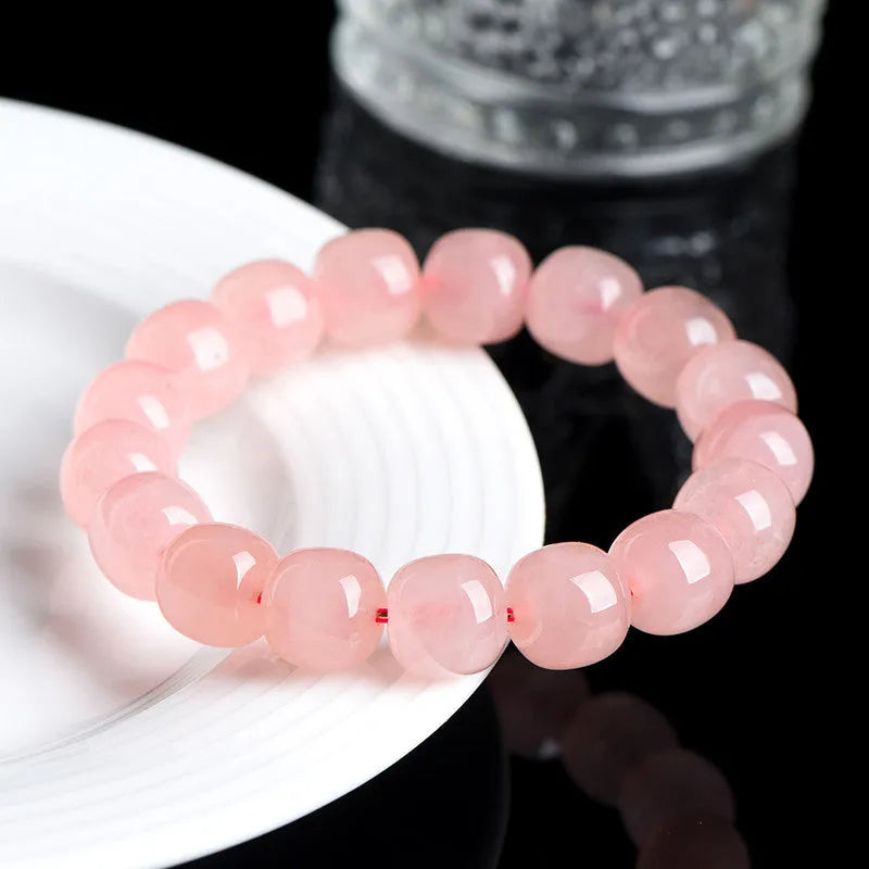 Pink natural crystal barrel bead bracelet with geometric beads on an elastic cord.