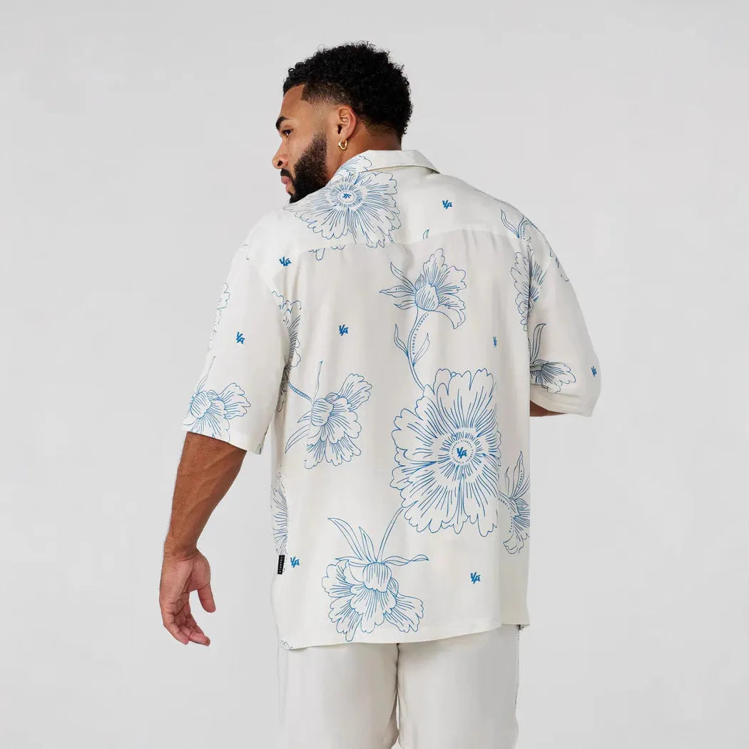 Man wearing a loose-fitting grey short-sleeve top with a floral print design.
