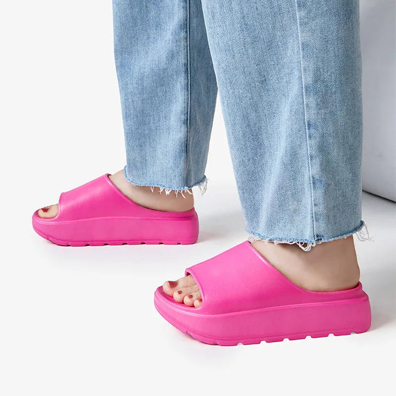 Women's beige thick-soled beach slippers with a fish mouth design on a wooden floor.