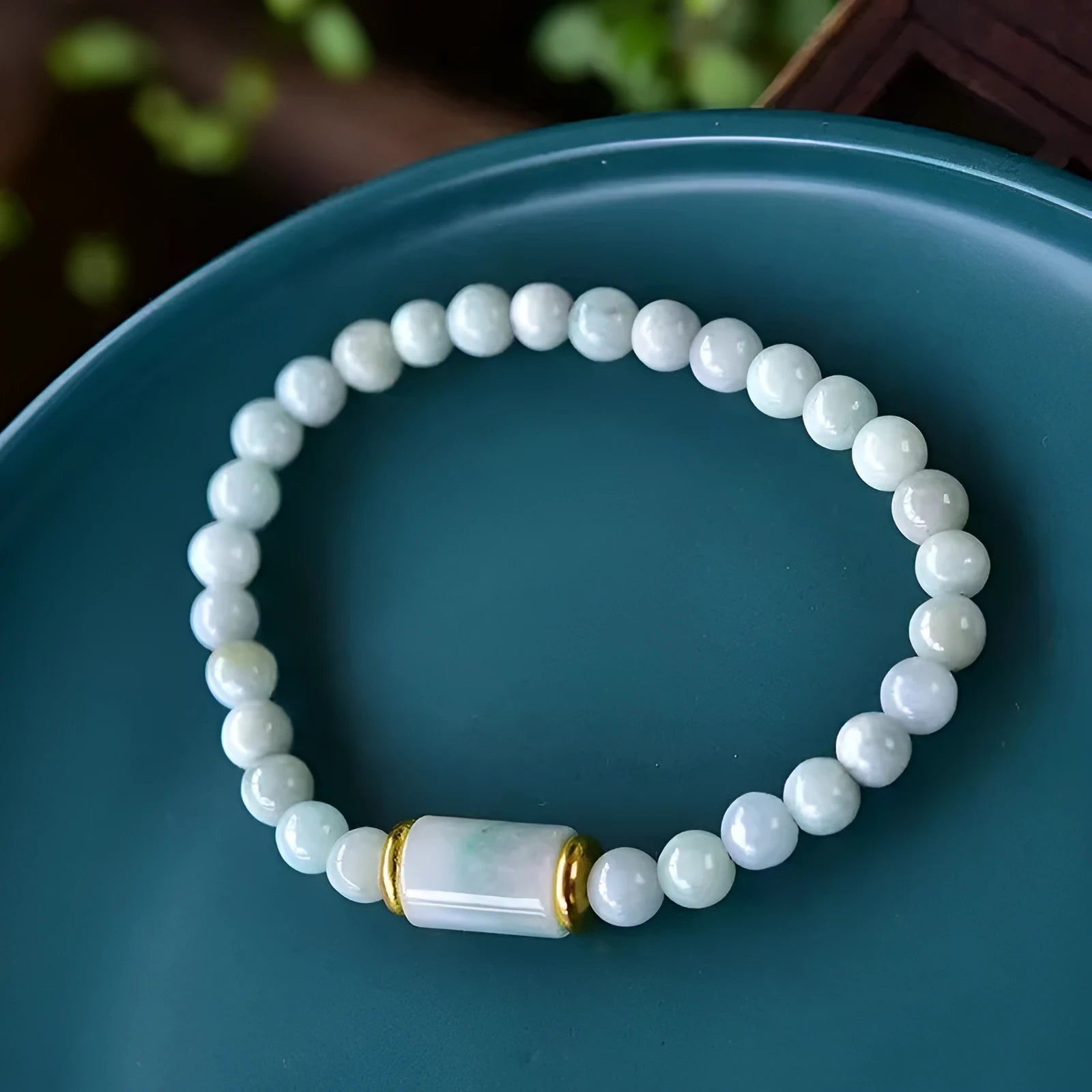 Close-up of a geometric jade bracelet with round emerald-coloured beads on a wrist.