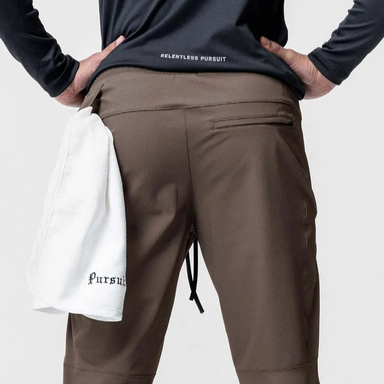 Men's loose grey fitness trousers with elasticated ankle ties on a gym floor.