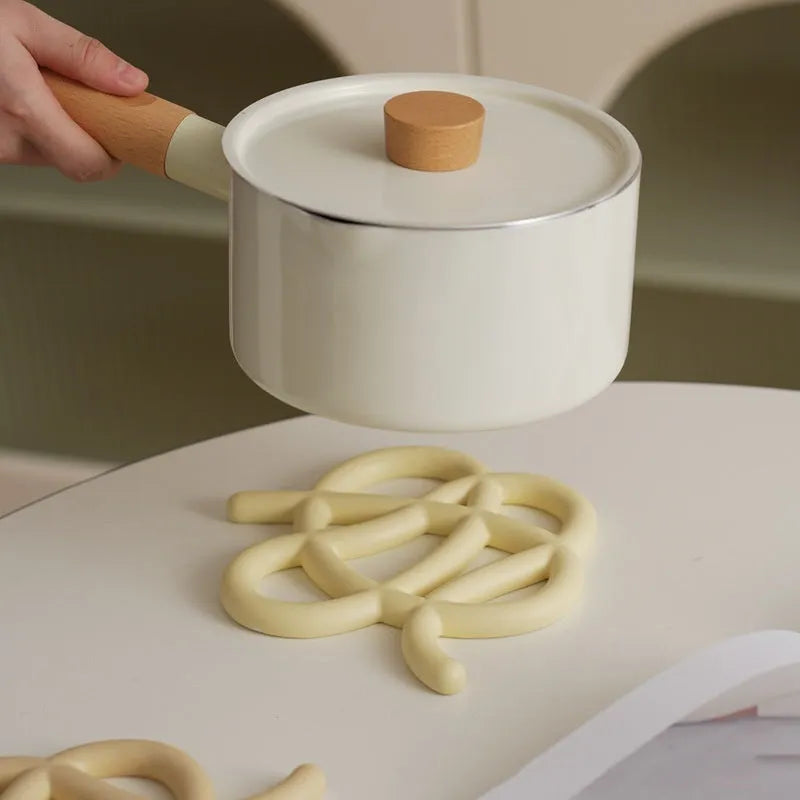 Ceramic heat proof mat in an irregular shape on a kitchen table, shown in a solid colour.