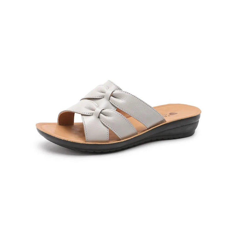 Women's beige cowhide slippers with a soft sole, shown from the side.