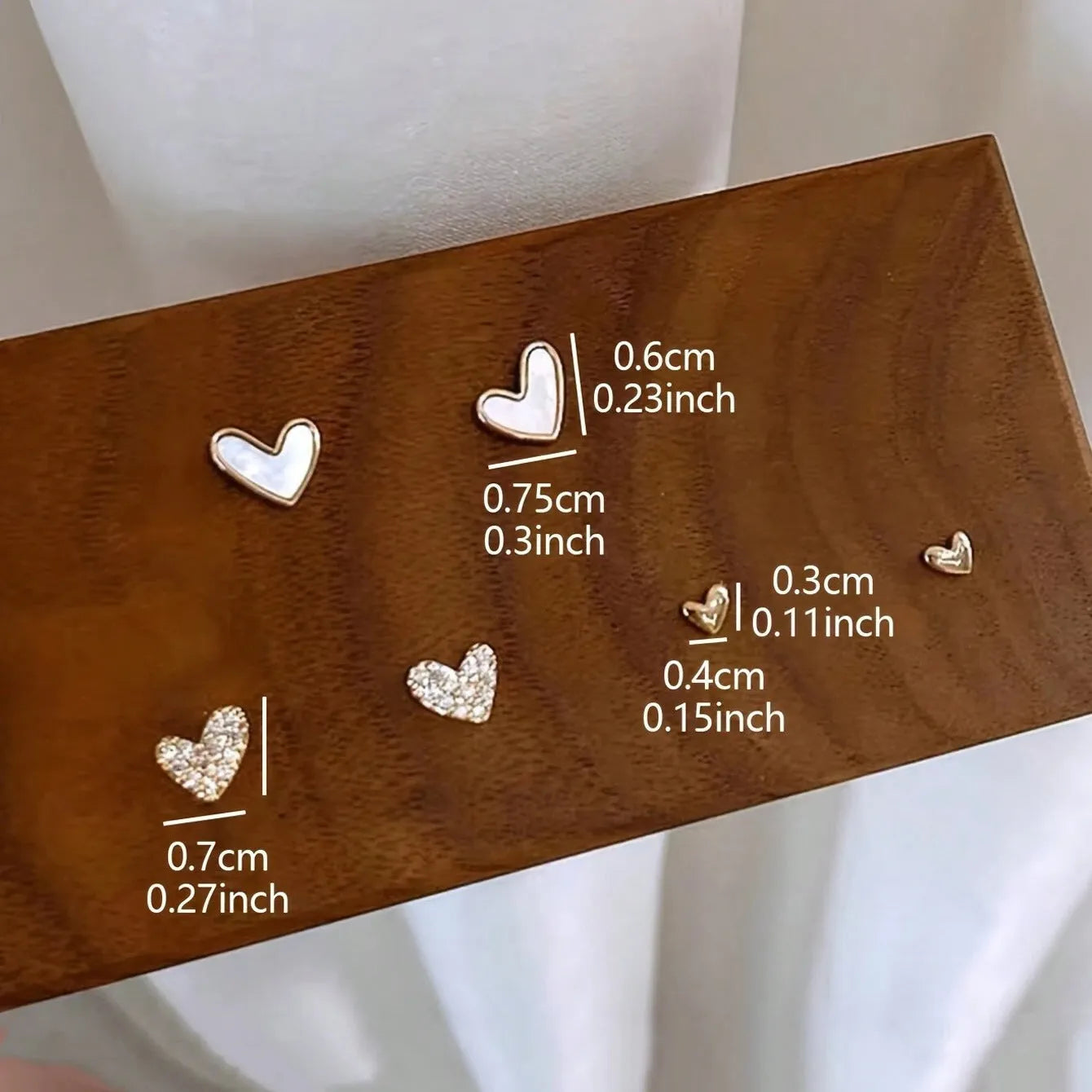 Three pairs of women's alloy heart-shaped earrings in gold, black, black-white, and pink colours