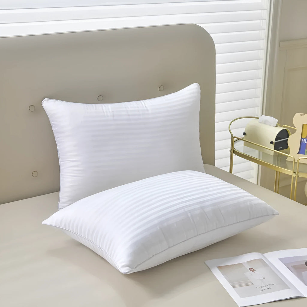 White cotton satin stripe feather and cotton pillow shown in a simple style on a bed.