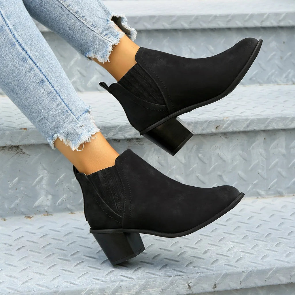Black women's ankle boots with a pointed toe and thick square heel on a rubber sole.