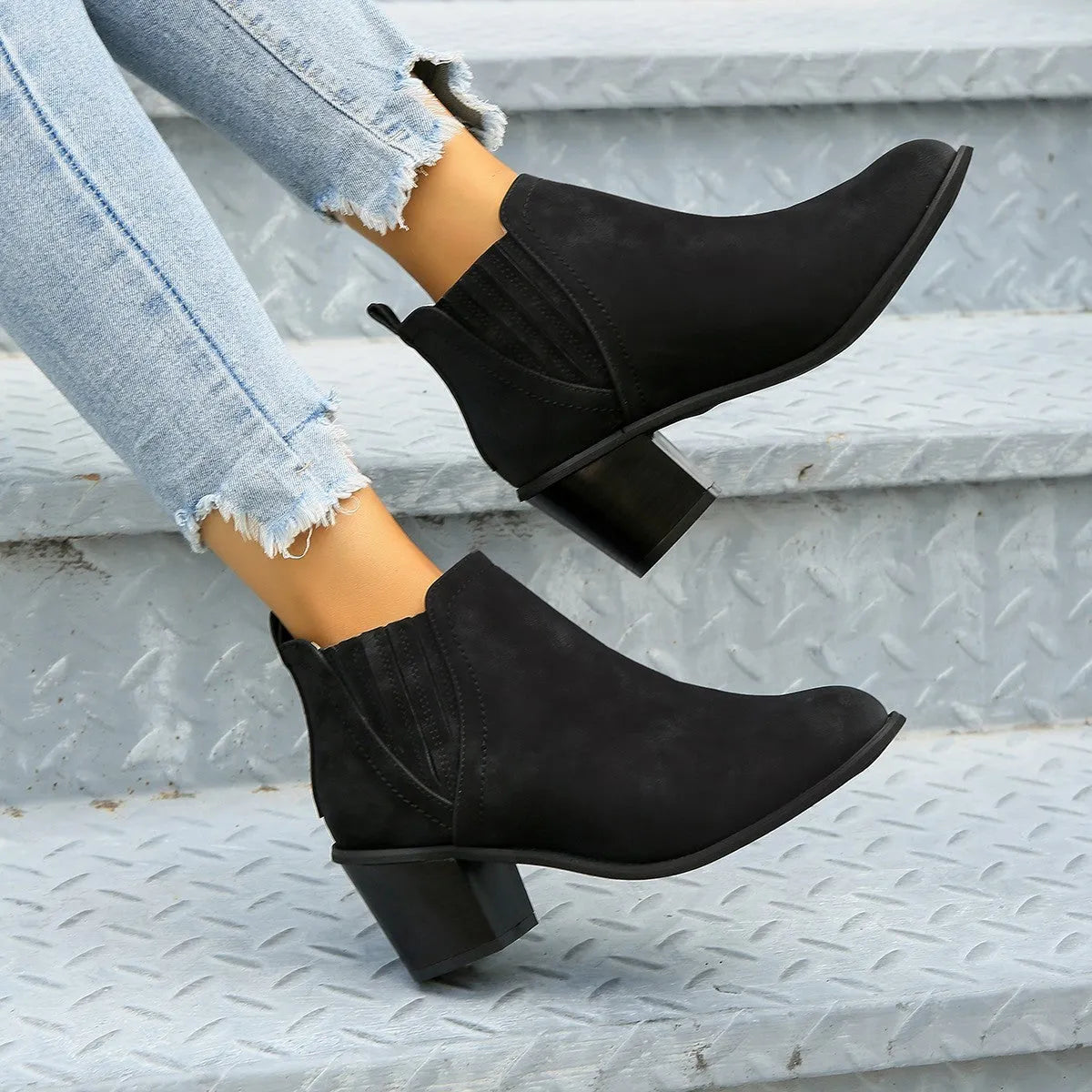Black women's ankle boots with a pointed toe and thick square heel on a rubber sole.