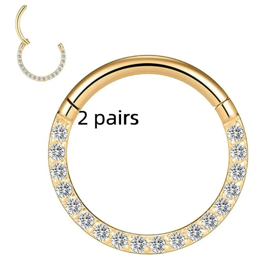 A pair of polished stainless steel seamless nose rings with a diamond-shaped front detail on a grey background.