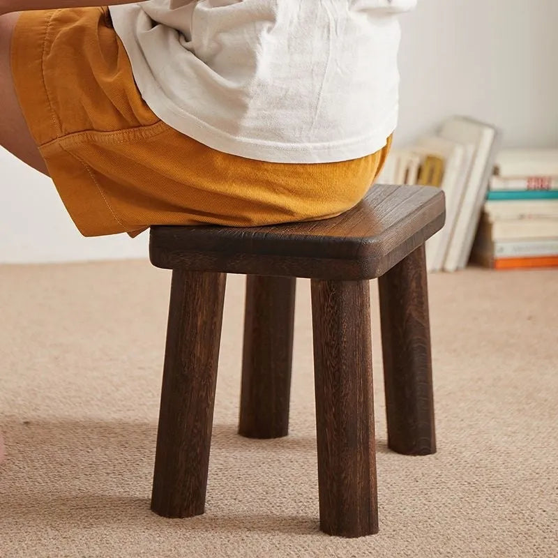 Solid wood household shoe changing stool with a distressed finish and bracket structure legs.