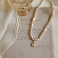 Vintage geometric pearl necklace with an adjustable chain from 21cm to 50cm on a grey background.