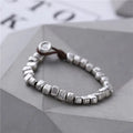 Women's handmade bracelet with irregular silver squares and wooden accents on elastic band