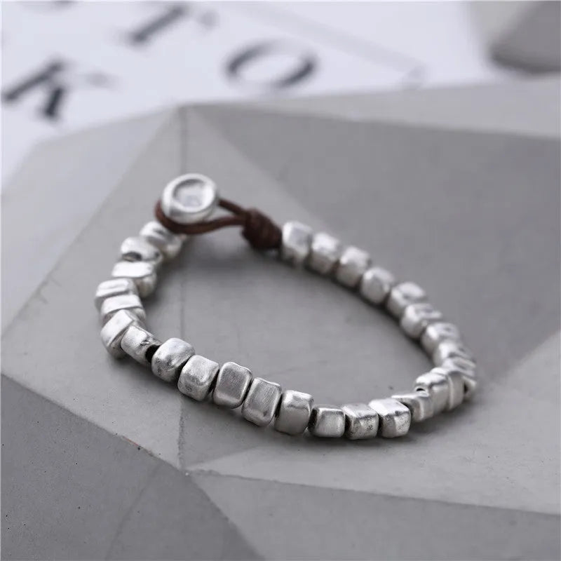 Women's handmade bracelet with irregular silver squares and wooden accents on elastic band