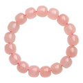 Pink natural crystal barrel bead bracelet with geometric beads on an elastic cord.