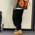 Men's black cotton harem pants with elastic waist and drawstring, cropped ankle bandage leg, side view